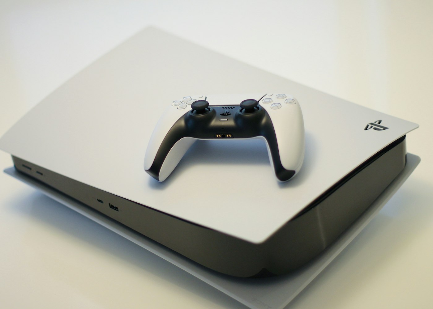 Witte PlayStation 5 met controller op een lichte tafel